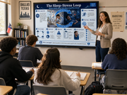 Teacher presenting on a screen titled 'The Sleep-Stress Loop' to students in a classroom.
