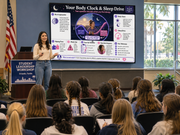 Woman presenting at a workshop titled 'Your Body Clock & Sleep Drive' to an audience.