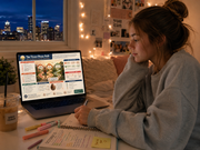 Person sitting on a couch with a laptop, notebook, and colorful markers in a cozy room with cityscape view.