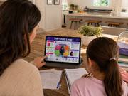 Two people using a tablet with an educational app in a kitchen setting